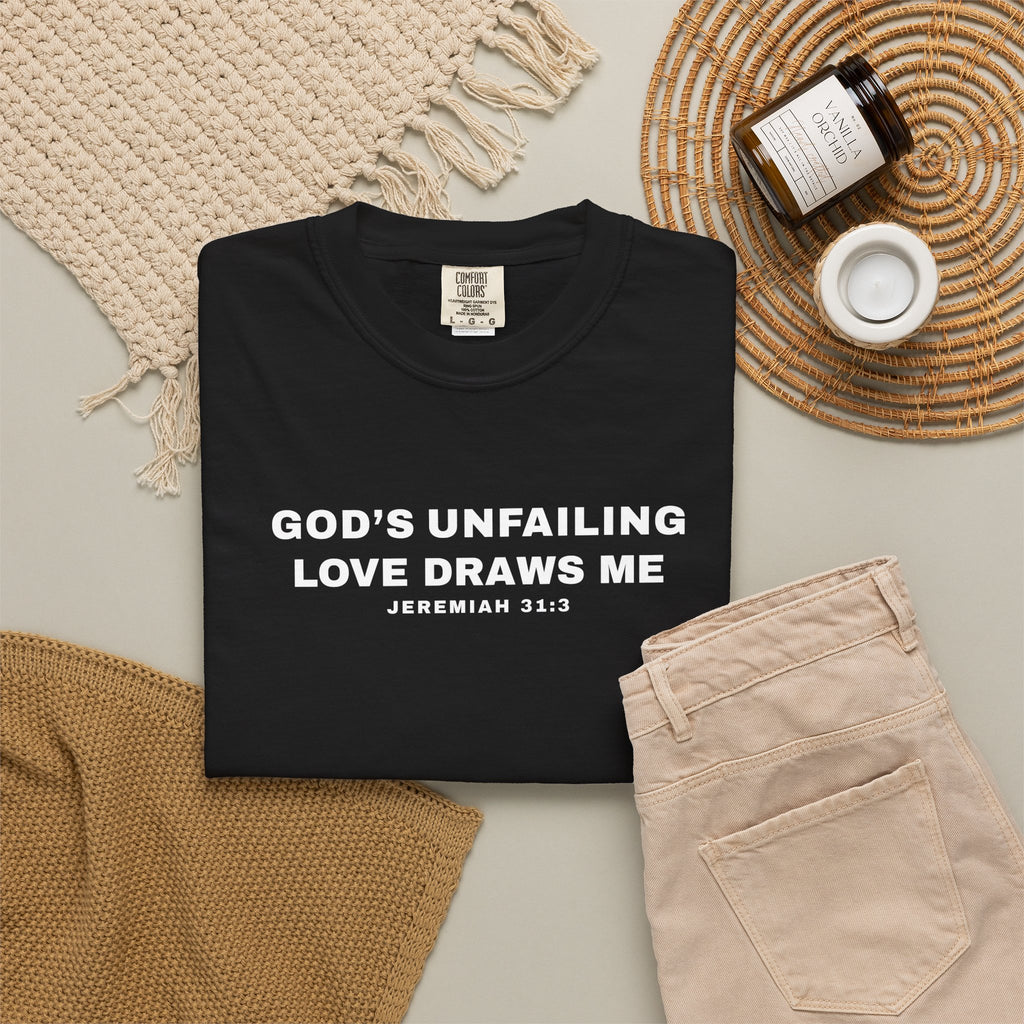 Black t-shirt with 'God's Unfailing Love Draws Me' text on a neutral background