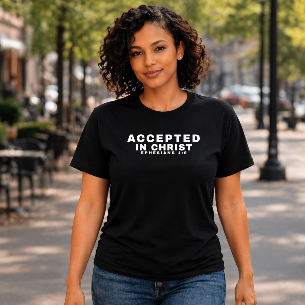 Person wearing a black t-shirt with 'Accepted in Christ' text on a city street.