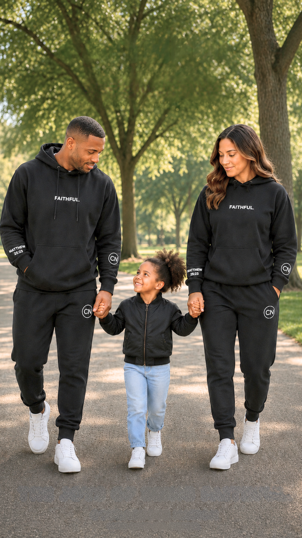 Family of three walking in the park on a beautiful day. Adults are wearing matching black outfits with FAITHFUL, MATTHEW 25:23 visible.